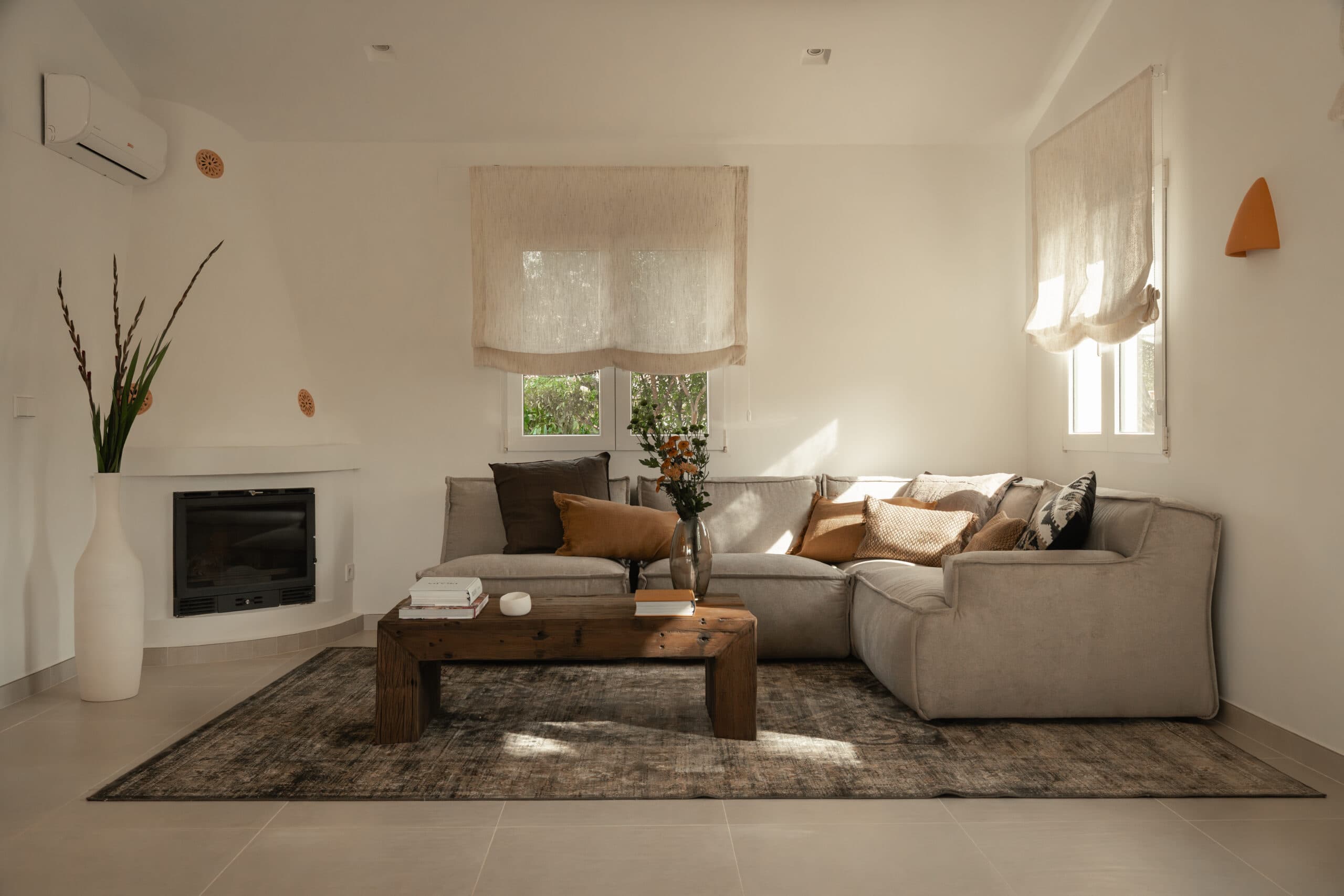 Salón con sofá modular beige, chimenea y mesa baja de madera rústica