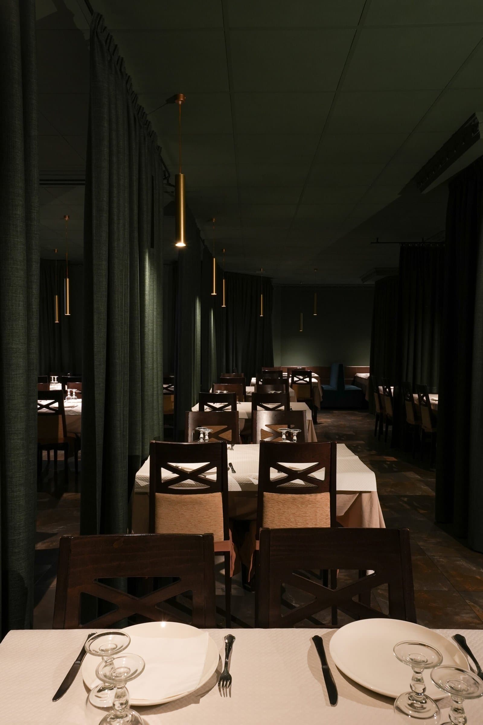 Set table in the foreground of a dimly lit restaurant dining room