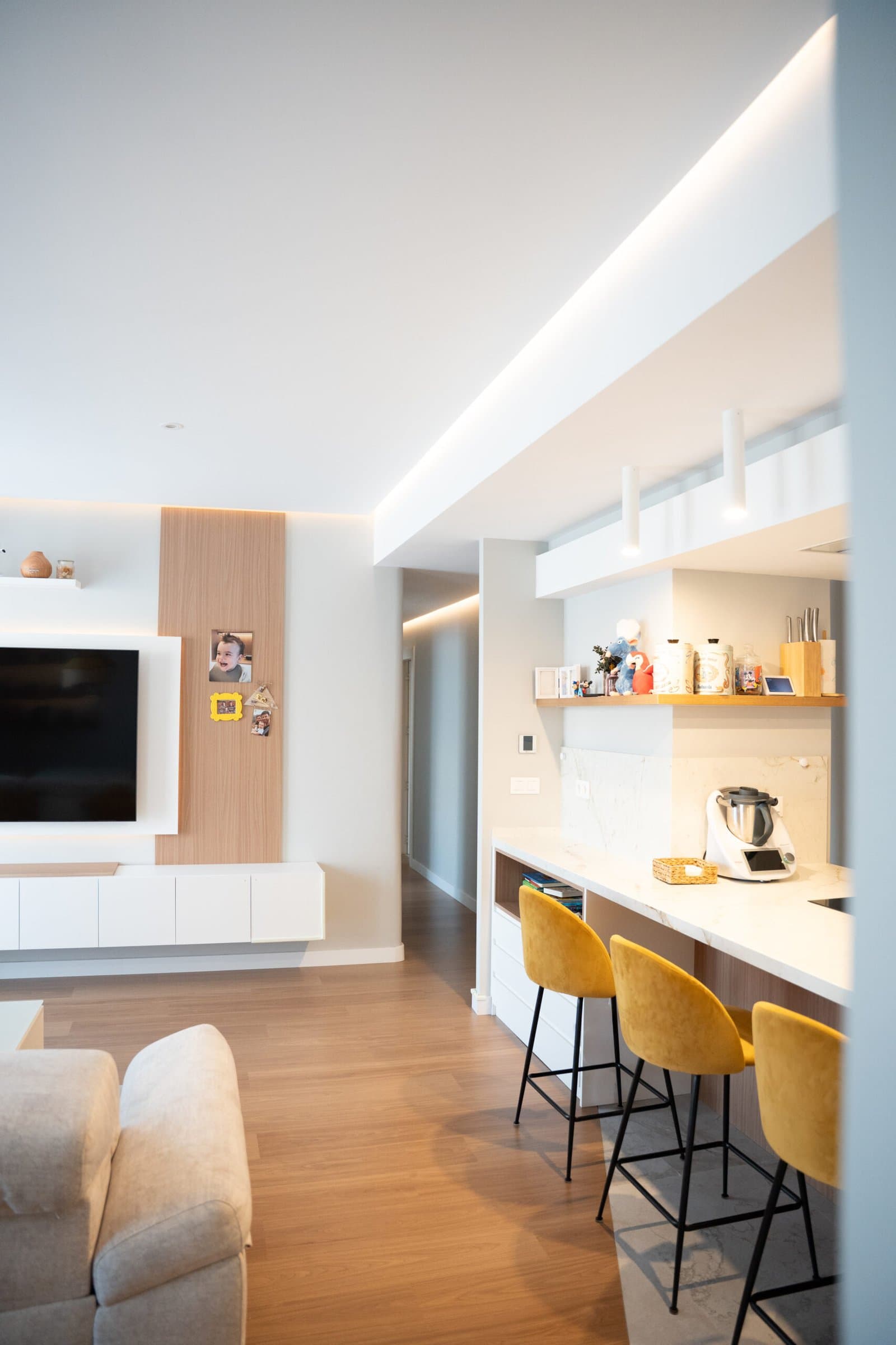 Open-plan living room with a white breakfast bar and mustard stools