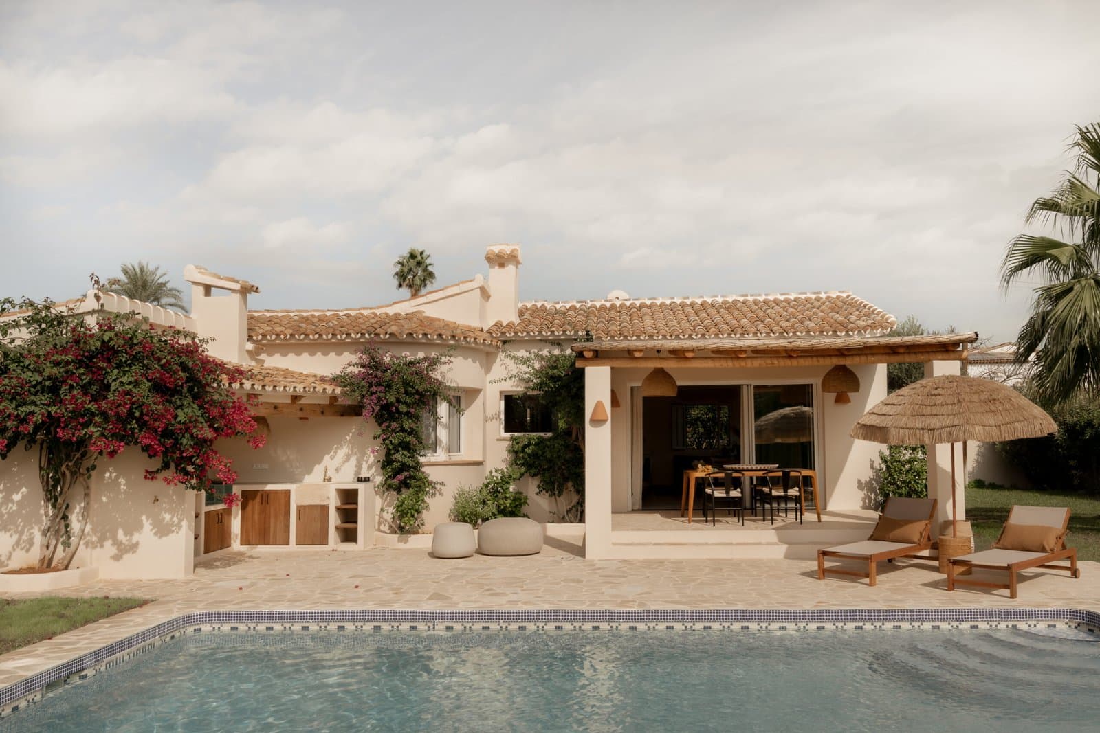 Exterior of the house with the pool, parasols and bougainvillea in flower