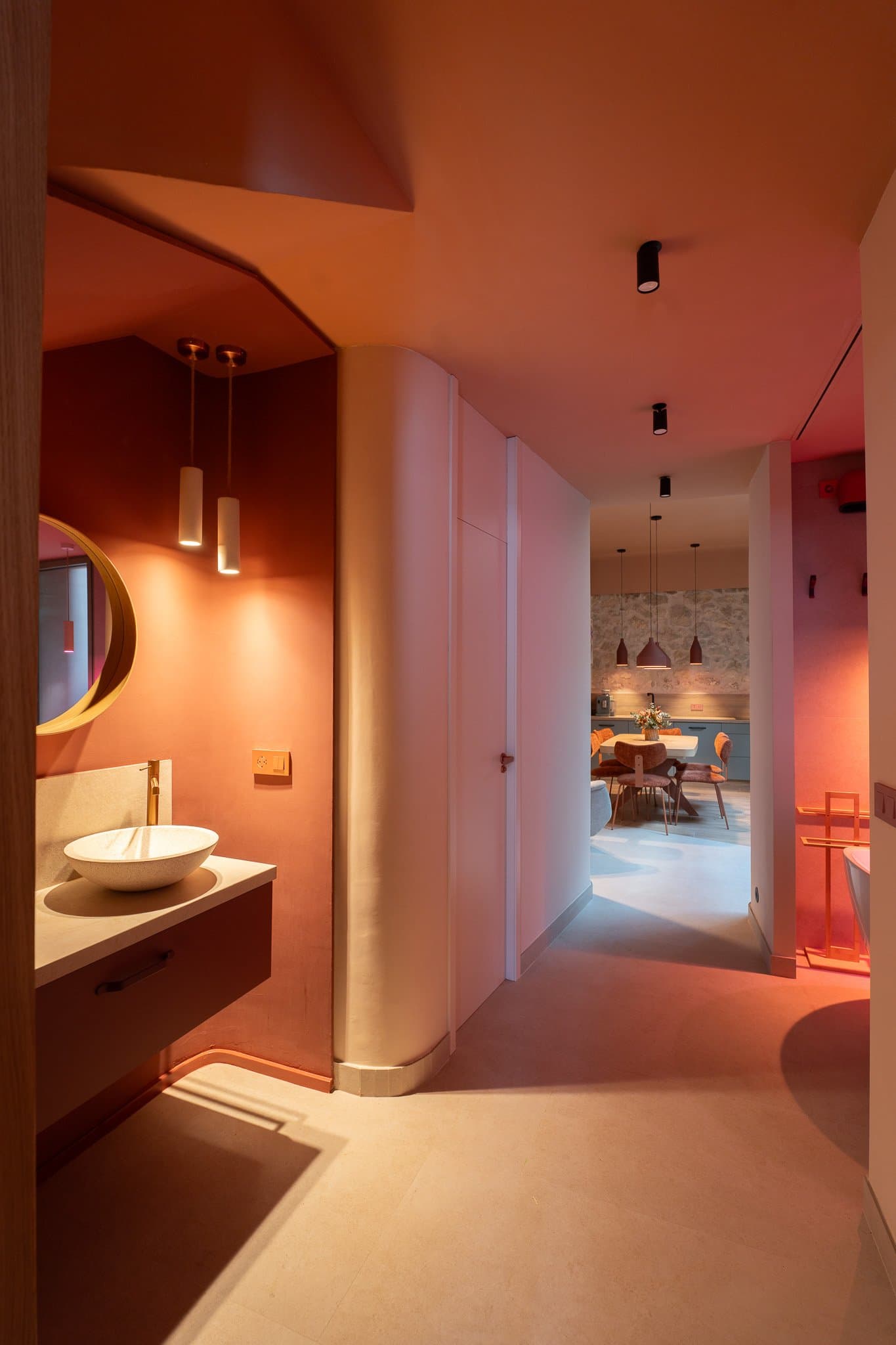 Terracotta-toned hallway with a round mirror, washbasin and a view into the dining room