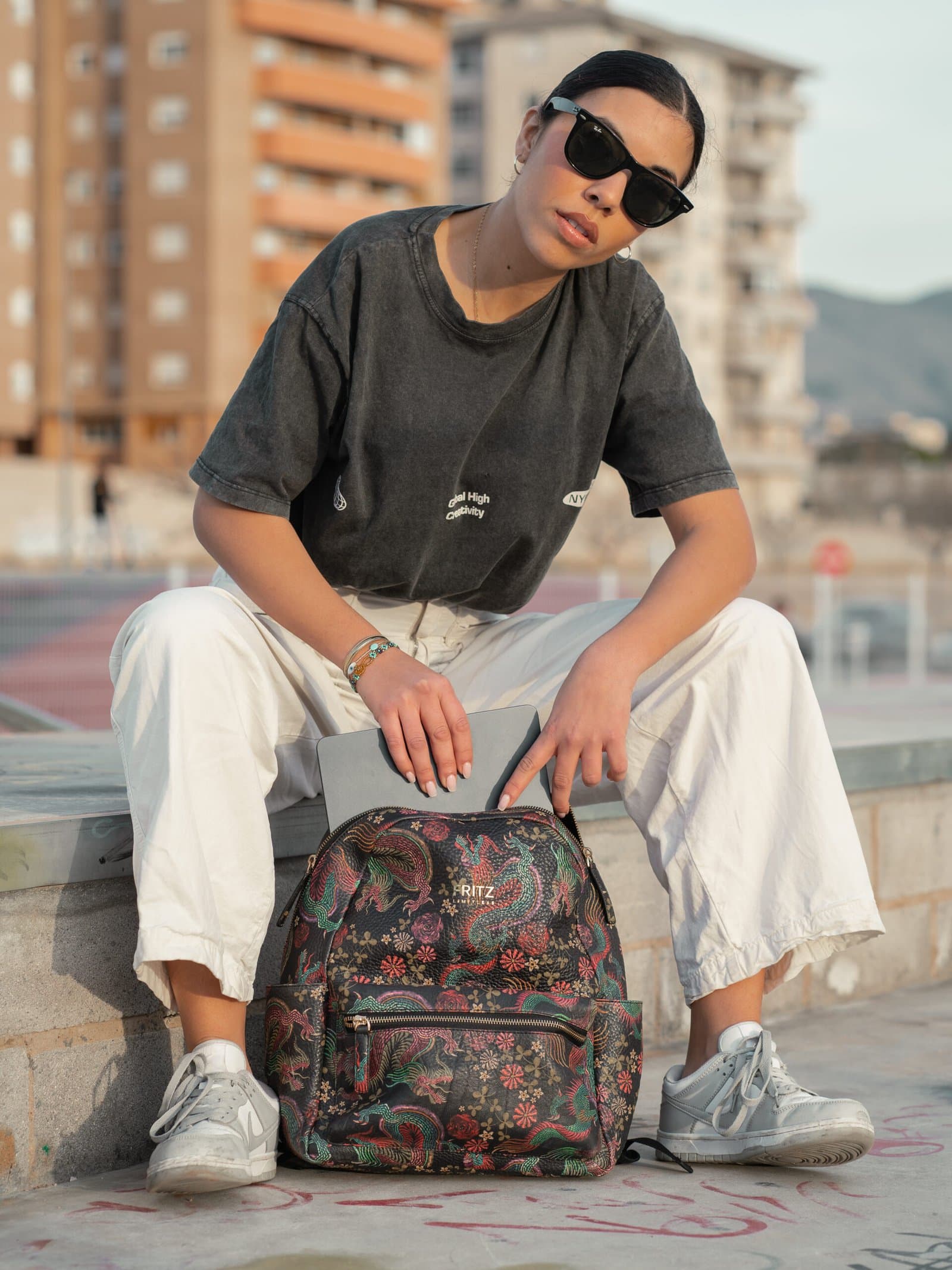 Person seated on a ledge with a floral-print backpack