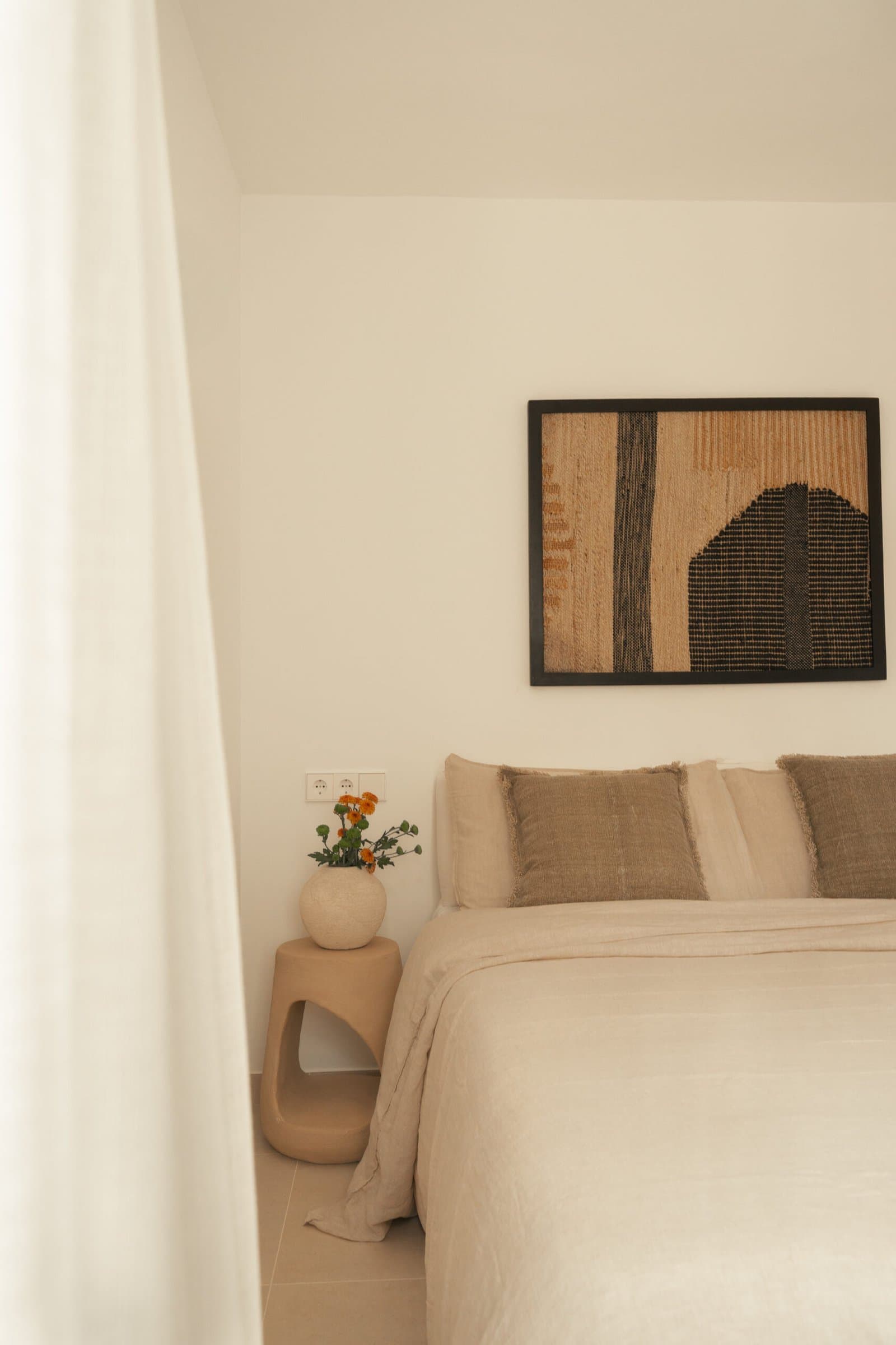 Bedroom detail: framed artwork above the bed and a sculptural bedside table