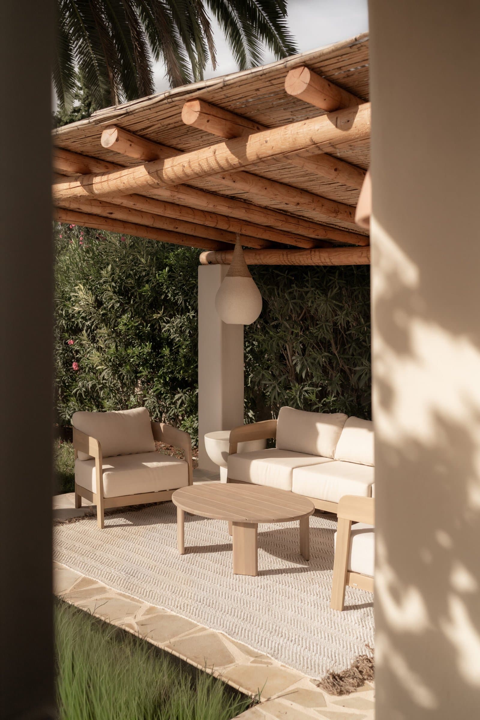 Covered outdoor lounge with cream sofas under a wooden pergola