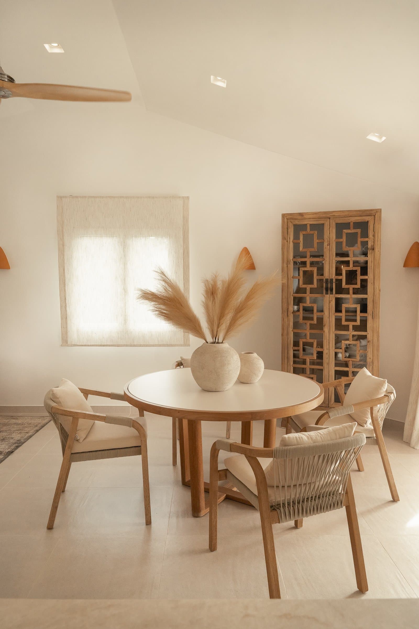 Dining corner with a round table, woven chairs and dried pampas grass