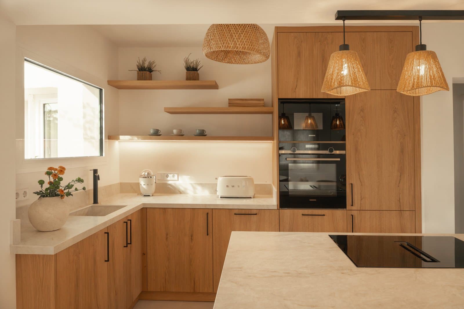 Oak kitchen with woven pendant lamps and a beige stone worktop
