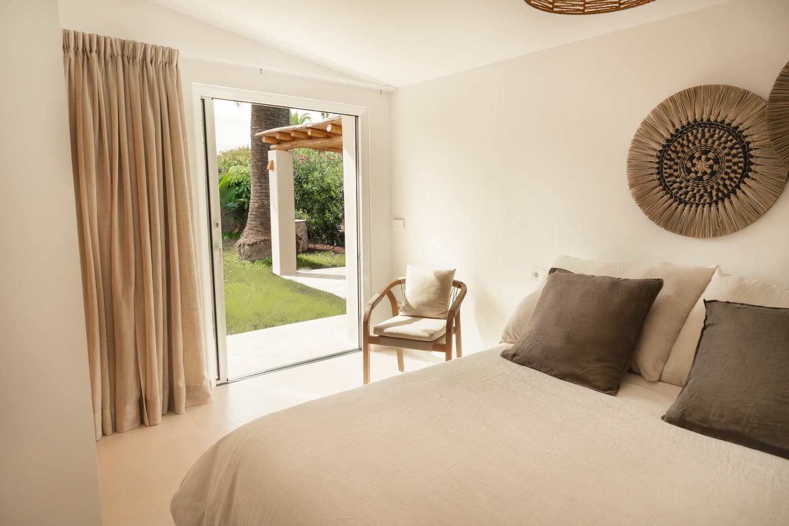 Bedroom with garden doors, woven wall art and linen bedding