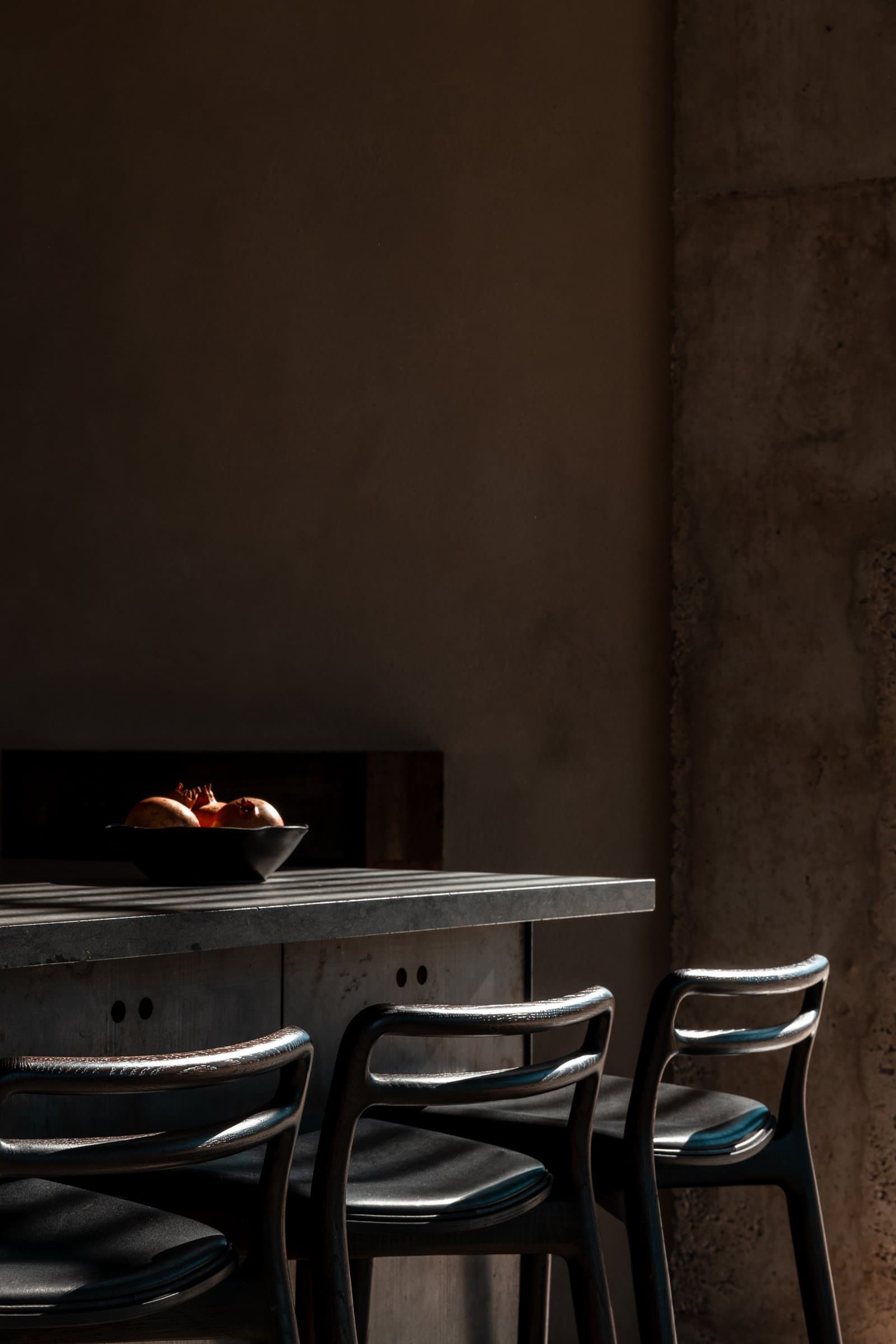 Dining table and dark wooden chairs against a concrete wall