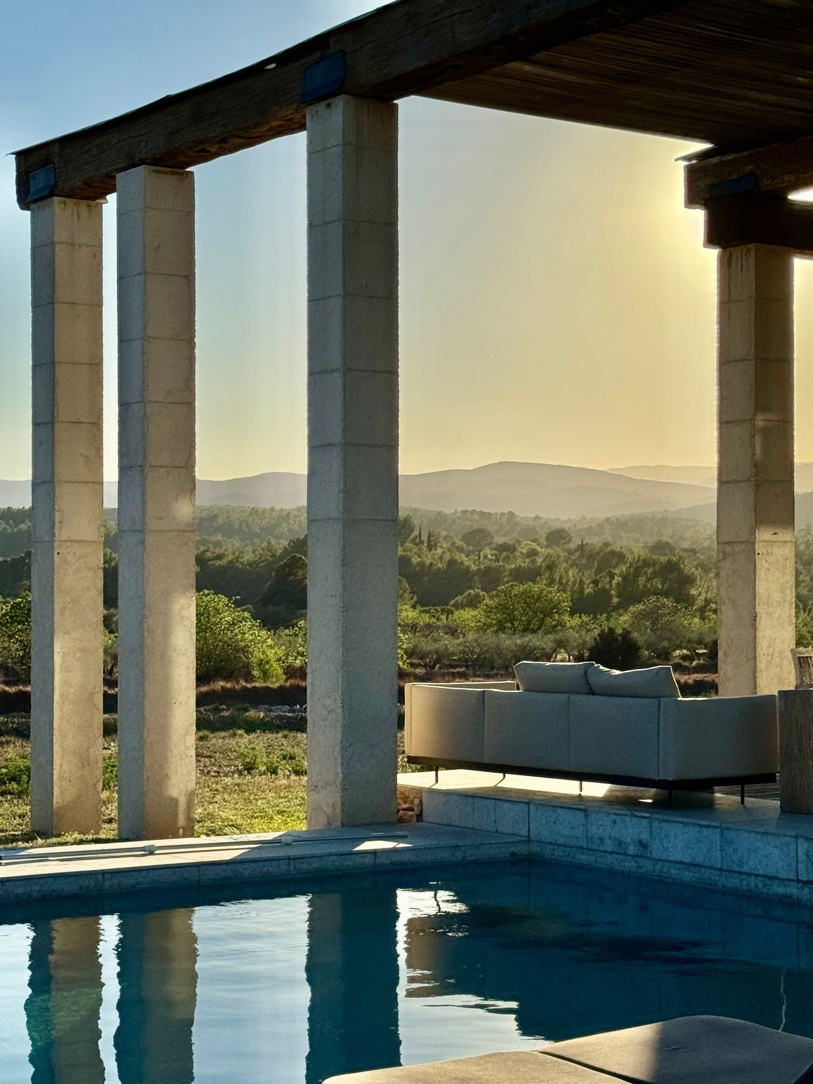 Pool framed by stone columns with mountain views at sunset