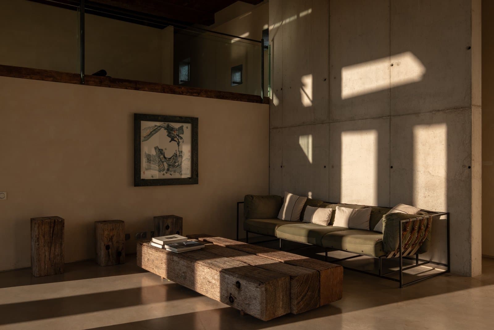Living room with concrete walls, a linen sofa and rustic wooden blocks as tables