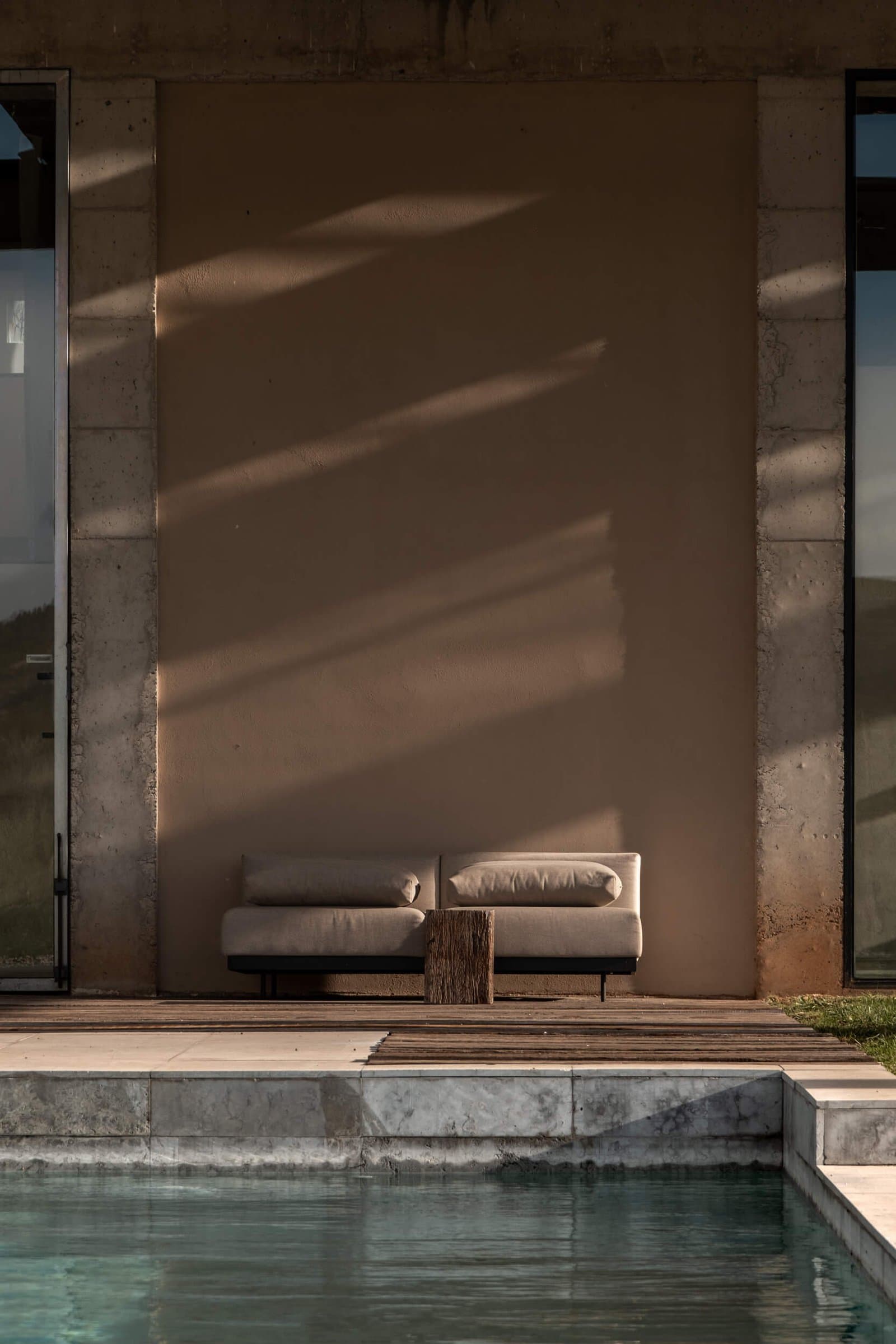 Pool beside the house with an outdoor sofa in the sun