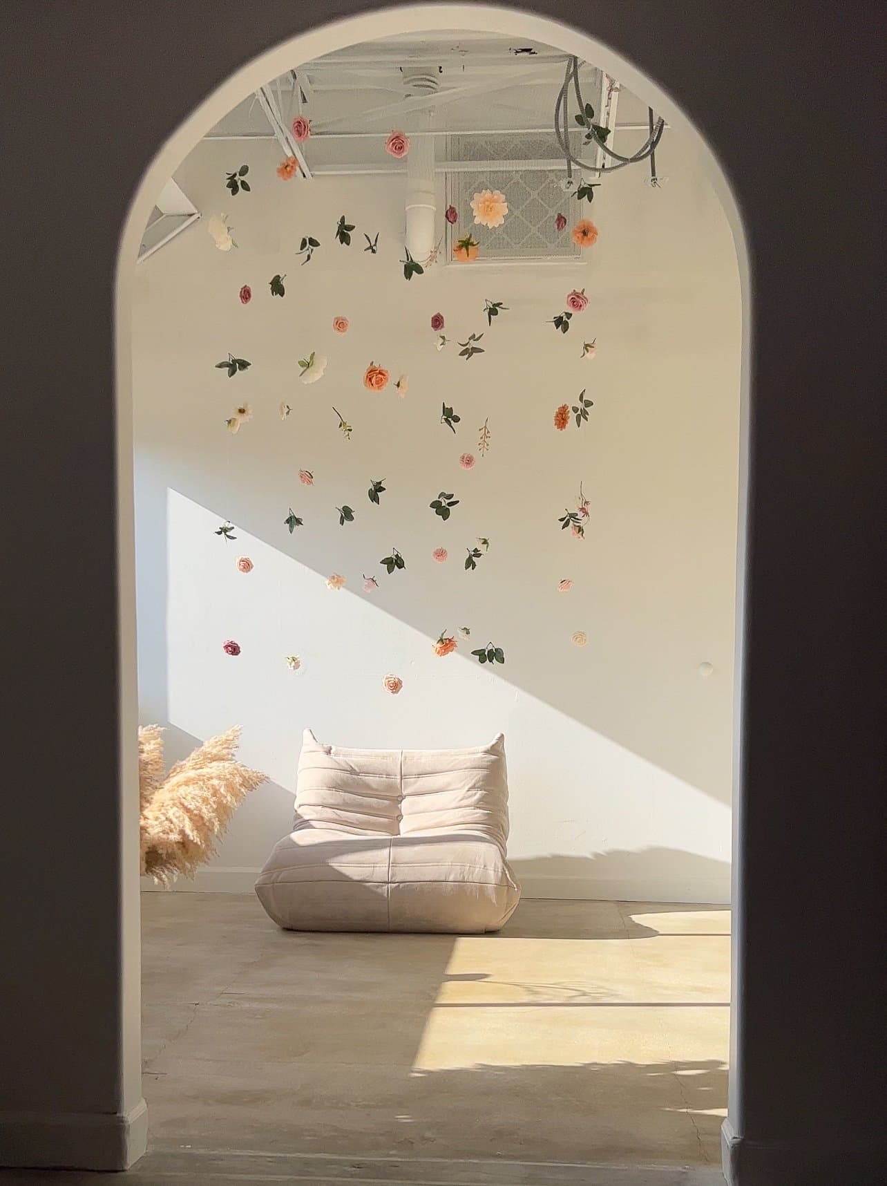 Arched doorway with dried flowers hanging, a cream sofa beyond